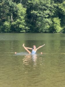 Amy balancing on one leg while standing in a lake and holding her right leg up in the air