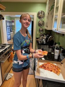 Amy standing in our kitchen next to the pizza that she made at her internship 