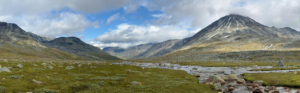 panoramic view of mountains, blue sky, white clouds, green grass in Norway