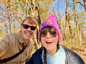 Carl and Sarah smiling with the woods behind them